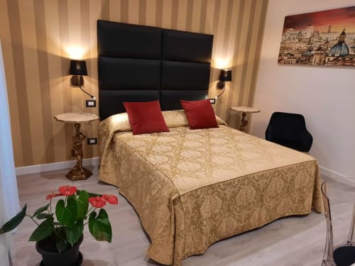 Camera elegante alla Maritza Guest House Roma con letto matrimoniale, testiera nera, cuscini rossi, carta da parati rigata