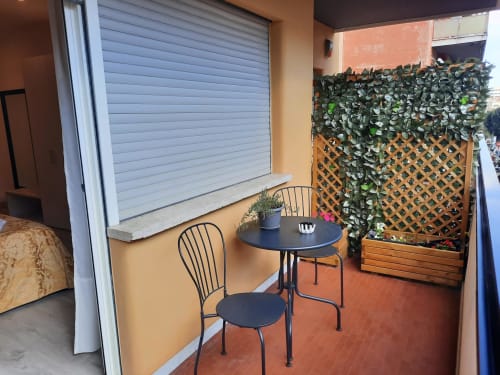 Area lounge sul balcone della Maritza Guest House Roma con tavolo, sedie e parete verde con rampicanti vista città