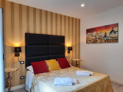 Camera moderna alla Maritza Guest House di Roma con testata nera, carta da parati rigata, cuscini rossi e oro, lampade comodino