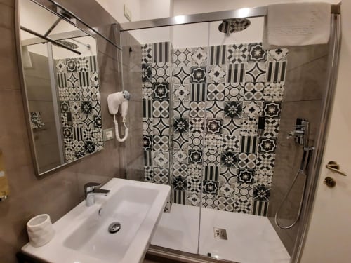Bagno moderno della Maritza Guest House a Roma con piastrelle bianco e nero, doccia walk-in e lavabo
