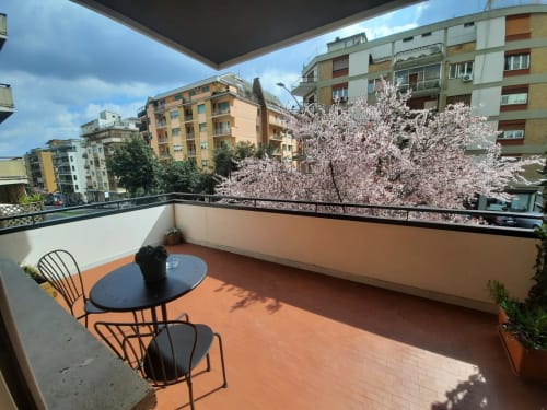 Soleggiata terrazza della Maritza Guest House a Roma con ciliegi in fiore, vista sulla città e arredo moderno