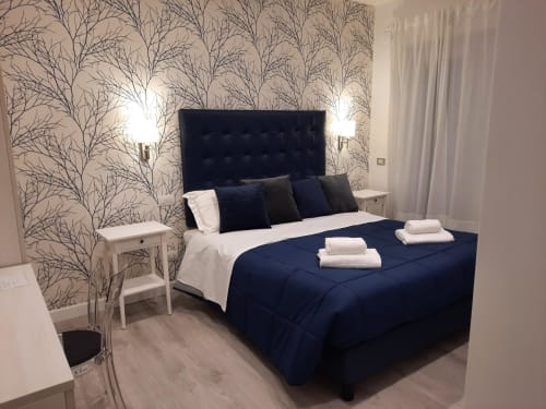 Camera elegante della Maritza Guest House a Roma con testata blu scuro, biancheria blu navy, carta da parati decorativa con alberi e letti gemelli