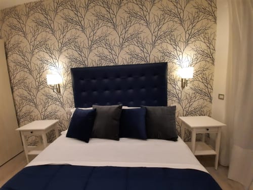 Camera moderna alla Maritza Guest House Roma con testata capitonné nera, cuscini blu navy, carta da parati a motivi naturali e comodino