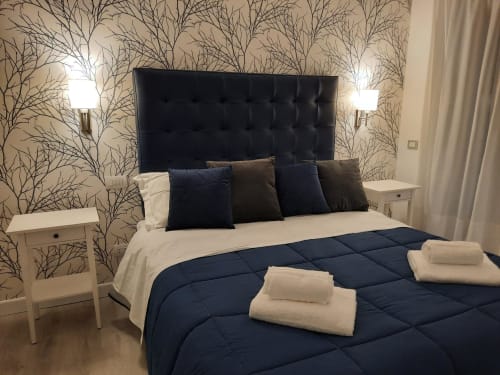 Camera moderna alla Maritza Guest House di Roma con testata nera trapuntata, biancheria blu navy, carta da parati decorativa con rami