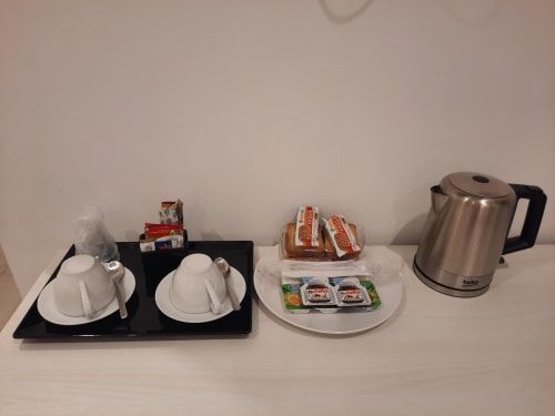Maritza Guest House Roma - Allestimento camera: bollitore, posate, pane, creme spalmabili e Nutella su piatto bianco
