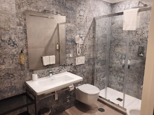 Bagno moderno della Maritza Guest House Roma con piastrelle grigie a motivi, lavabo bianco, wc e doccia walk-in con vetro
