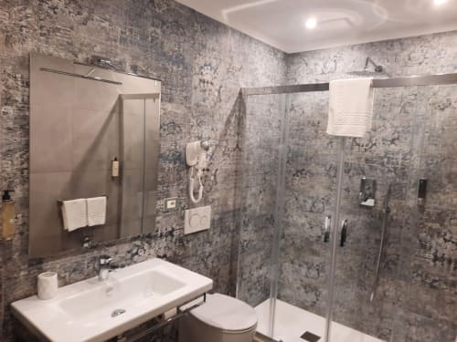 Bagno moderno della Maritza Guest House Roma con rivestimento in piastrelle grigie, lavabo bianco, box doccia e specchio illuminato