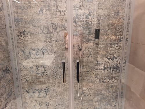 Moderna cabina doccia con rivestimento in piastrelle grigio anticato e rubinetteria nera presso la Maritza Guest House di Roma
