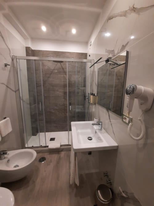 Bagno moderno della Maritza Guest House Roma con doccia in vetro, lavabo bianco, wc e asciugacapelli