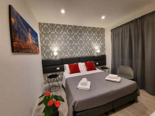 Camera Baldo con 4 letti presso Maritza Guest House Roma: letto moderno, cuscini rossi, testata damascata, opere d'arte con vista città e grigio