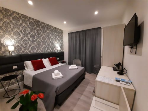 Maritza Guest House Roma - Camera Baldo 4 con vista sulla città, letto nero, cuscini rossi, carta da parati decorata, TV e comfort moderni