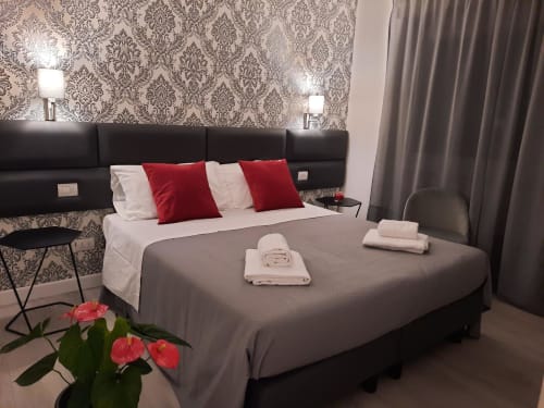 Camera Baldo della Maritza Guest House a Roma: letto grigio, cuscini rossi, carta da parati damascata e vista sulla città