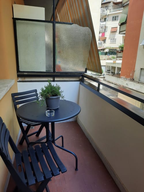 Piccolo balcone della Maritza Guest House Roma con tavolo nero, sedia e pianta in vaso con vista sulla città