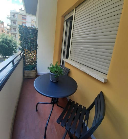 Balcone della Maritza Guest House a Roma con tavolo rotondo, sedia, pianta in vaso e vista sulla città