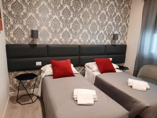 Camera Baldo 4 della Maritza Guest House Roma con due letti, cuscini rossi, carta da parati damascata e testata moderna nera.