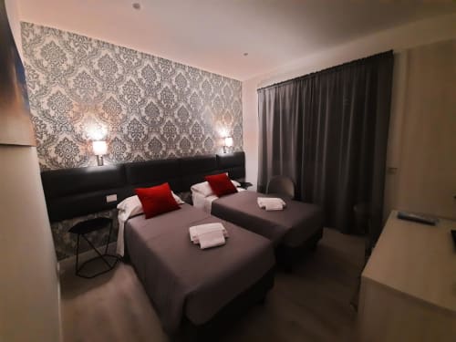 Camera doppia Baldo 4 della Maritza Guest House Roma con carta da parati damascata, accenti rossi, letti grigi e tende scure