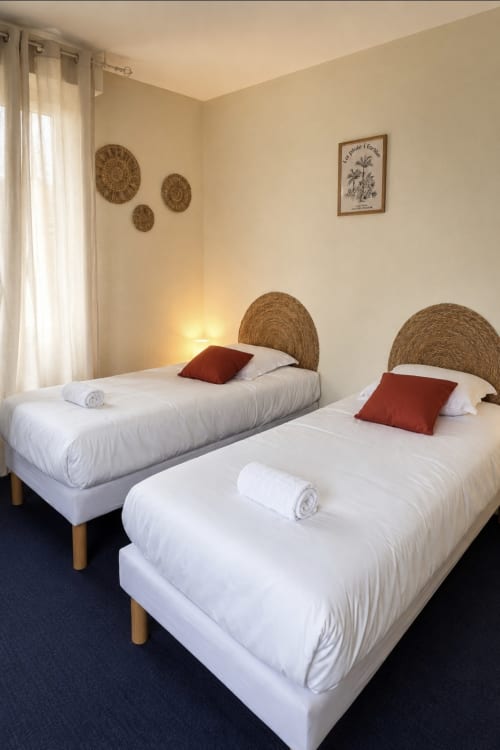 Chambre twin de l'hôtel Aux Genêts d'Or à Trévé, France avec têtes de lit tissées et touches de couleur bordeaux