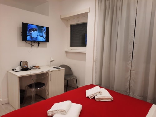 Camera moderna presso Maritza Guest House Roma con letto rosso, TV a schermo piatto, scrivania e vista sulla città