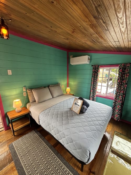 Bright green bedroom with turquoise trim at BarrBra BnB in Bocas del Toro, featuring queen bed and sea view windows
