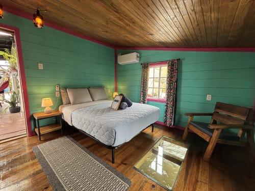 Bright green and pink beachfront bedroom at BarrBra BnB in Bocas del Toro with queen bed, wooden ceiling, and modern