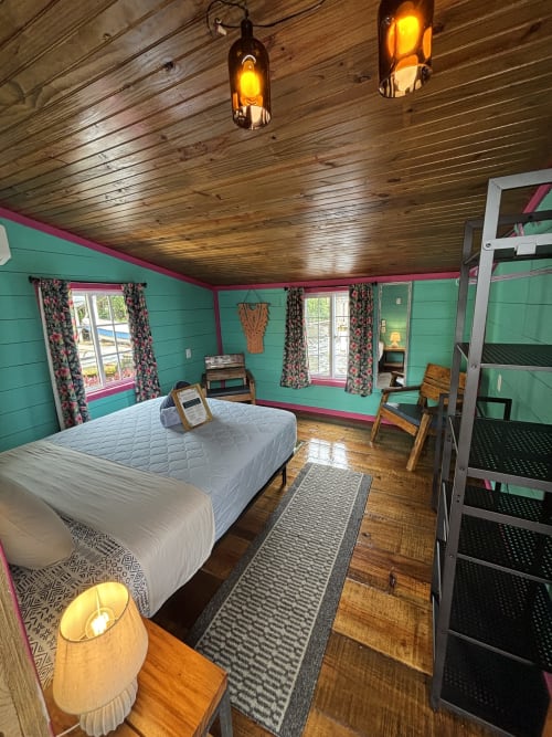 Bright turquoise bedroom at BarrBra BnB in Bocas del Toro with wooden ceiling, bunk beds, and sea view windows