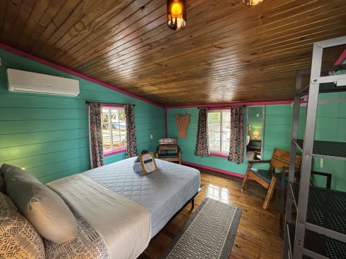 Chambre lumineuse turquoise et rose au BarrBra BnB à Bocas del Toro avec plafond en bois, lit queen-size et vue sur mer