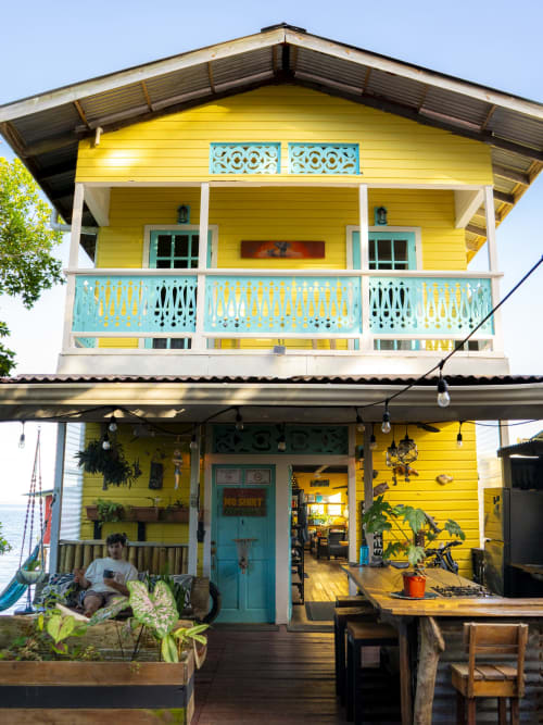 Bright yellow Caribbean beach house with turquoise railings and shutters in Bocas del Toro, Panama - BarrBra BnB waterfront