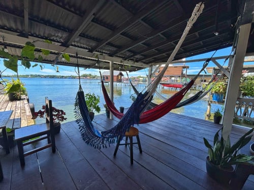 Colorful hammocks on wooden overwater deck at BarrBra BnB in Bocas del Toro with blue Caribbean Sea and wooden houses in