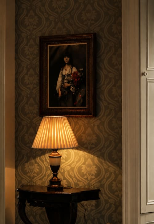 Élégant couloir de South Hill House avec portrait encadré, papier peint damassé et lampe de table éclairée