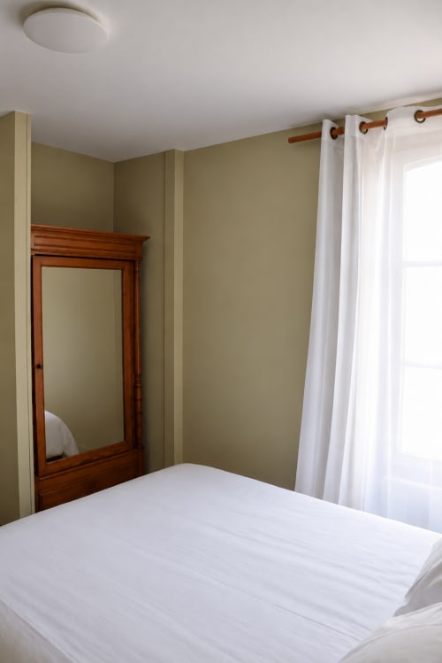 La Agathe bedroom at Au Bon Séjour hotel in Sainte-Suzanne-et-Chammes with white bedding, wooden mirror, and city views