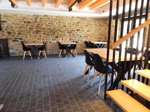 Comedor moderno del Hotel Izarbe en Burgos con muros de piedra, vigas de madera y sillas negras contemporáneas