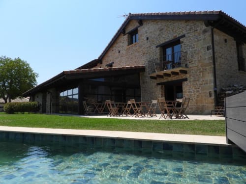 Hotel Izarbe en Burgos: edificio de piedra con piscina, terrazas y moderna extensión acristalada con vistas al jardín