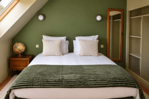 Chambre accueillante à Au Bon Séjour avec murs verts, literie blanche et mobilier en bois à Sainte-Suzanne-et-Chammes
