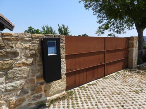 Entrada de puerta automática en Hotel Izarbe de Burgos con portero automático en muro de piedra