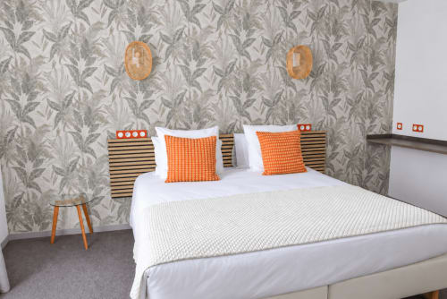 Chambre accessible à l'Au Bon Séjour avec lit queen-size, accents orangés et papier peint à motifs de feuilles