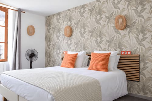 Modern accessible bedroom at Au Bon Séjour with orange pillows, patterned wallpaper, and wicker decor