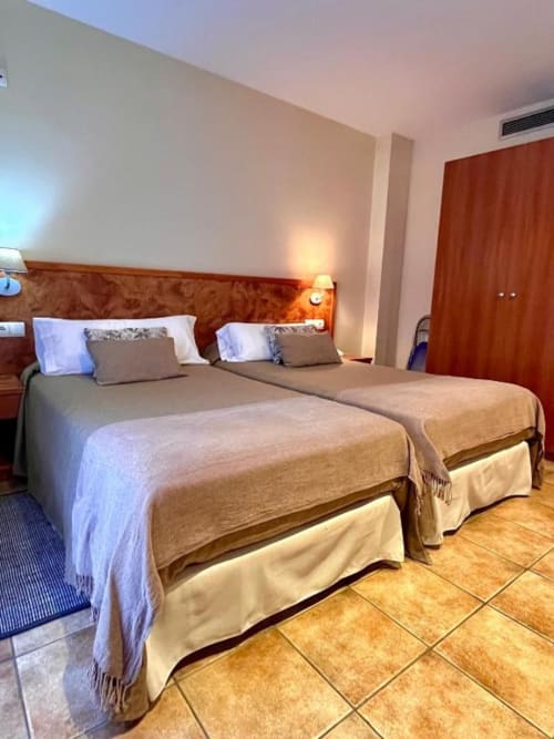 Habitación doble confort en Hotel La Muntanya de Llafranc con dos camas, cabecero de madera y suelo de baldosas