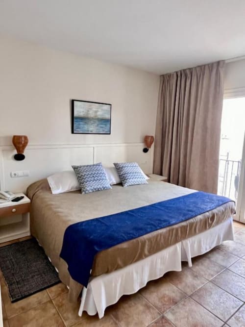 Lujosa habitación con cama king en Hotel La Muntanya de Llafranc, con pasillo azul, arte con vista al mar y acceso a balcón