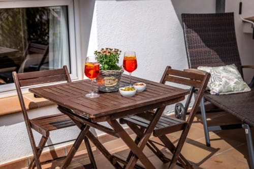 Terraza de madera con dos sillas, cócteles y flores del Hotel La Muntanya en Llafranc con vista al océano