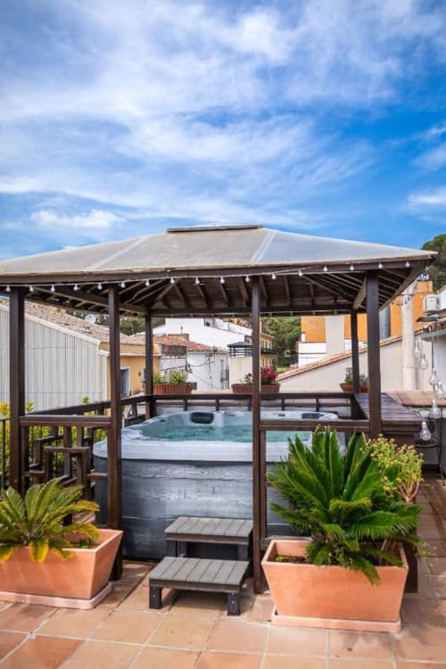 Gazebo techado junto a la piscina con bañera de hidromasaje en Hotel La Muntanya en Llafranc, rodeado de macetas de terracota y estilo colonial