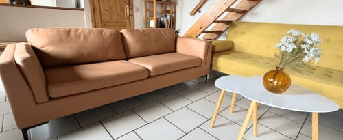 Séjour contemporain du gîte Aux 4 Chalets Corbion avec canapé caramel, mur jaune et table basse blanche