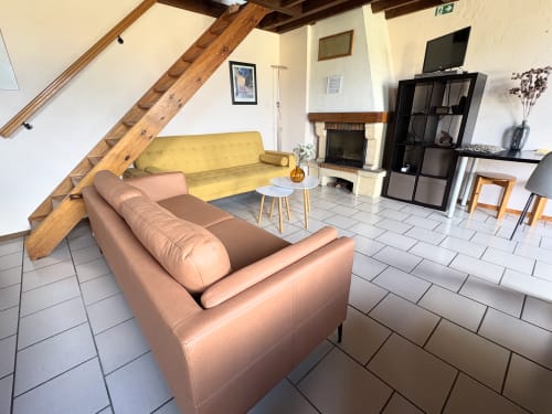 Spacieux séjour du Chalet 4 aux Aux 4 Chalets Corbion, Bouillon, avec fauteuil en cuir beige, canapé jaune et cheminée