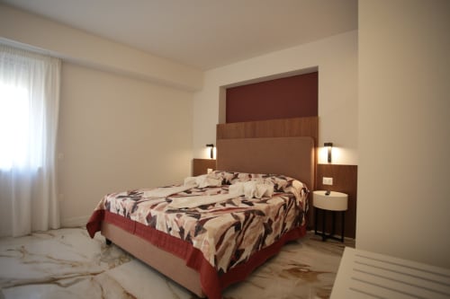 Camera moderna presso Totonno's Rooms a Tropea con biancheria decorativa, testata in legno e pavimento in marmo