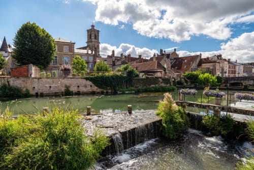 Vue pittoresque du fleuve à Ouagne avec clocher historique, bâtisses en pierre et architecture villageoise française charmante