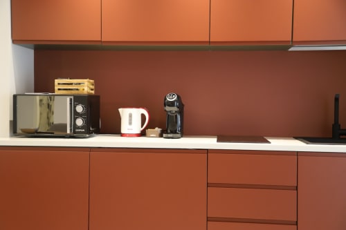 Angolo cucina moderno a Totonno's Rooms a Tropea con mobili in terracotta, microonde, bollitore e caffettiera su fondo bianco