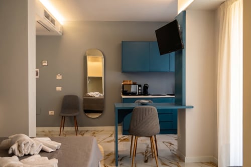 Camera moderna in Totonno's Rooms a Tropea con scrivania blu, TV e pavimento in marmo