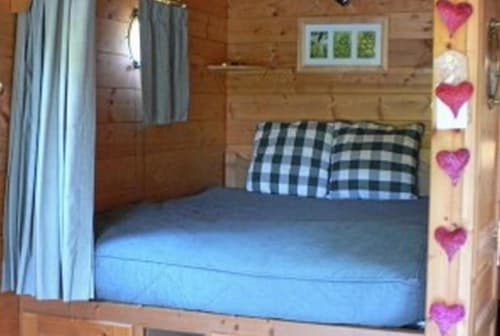 Chambre douillette au Relais de Maufront avec murs en bois, literie bleue, oreillers à carreaux et cœurs décoratifs