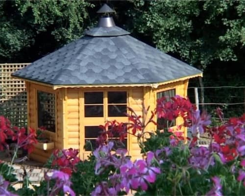 Pavillon de jardin en bois jaune avec toit noir au Relais de Maufront, entouré de fleurs violettes