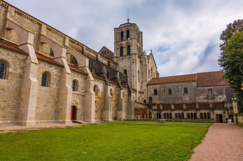 Cour de l'abbaye médiévale en pierre avec pelouse verdoyante et clocher du Relais de Maufront à Ouagne, France