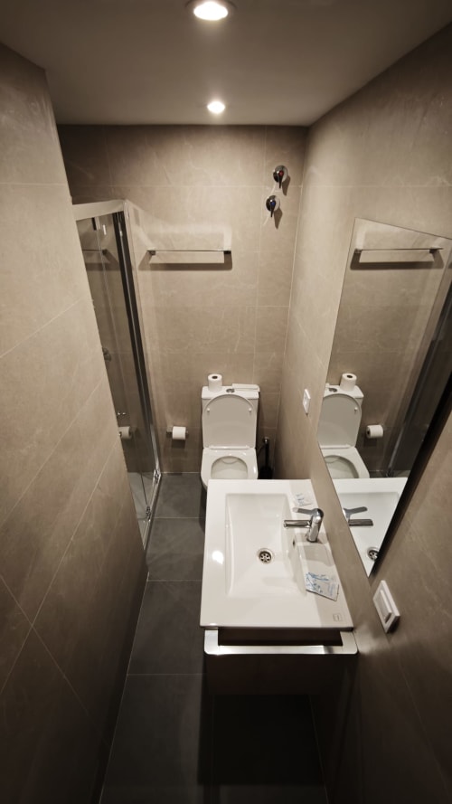 Baño moderno del Hotel Continental Calella con dobles lavabos, inodoros y cabinas de ducha de cristal
